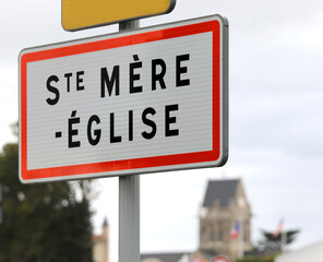 French road sign indicating the place where  the paratrooper hanging from the bell tower who fell during the Normandy landings