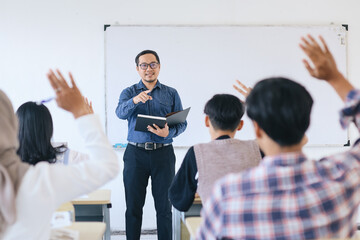 Lecturer pointing at college student with hand raised in classroom. Student raising a hand with a question for the teacher.  - obrazy, fototapety, plakaty
