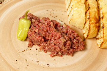 Raw beef tartar served on rye bread toasts close up. Ready menu. Selective focus
