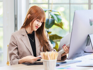 Portrait closeup shot Asian professional successful young female businesswoman creative graphic designer in casual fashionable suit outfit sitting smiling working with computer at workstation desk