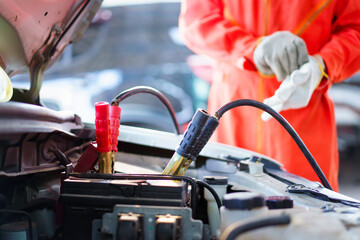 Professional roadside technician support using an emergency jump start cable to connect a battery from other car to the one which out of battery.