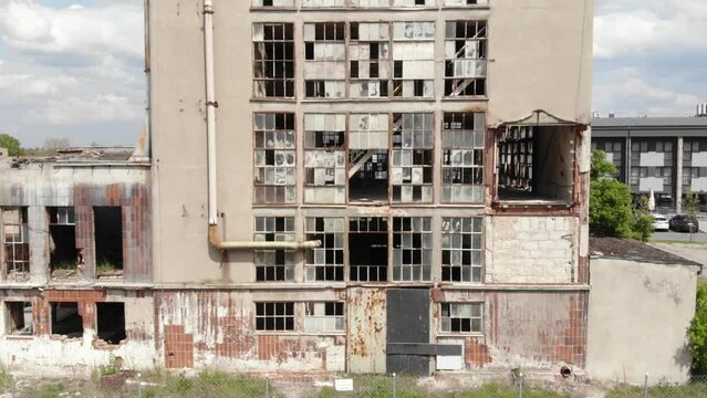 large, abandoned building with broken windows. The building is in a rural area of Cukrownia Żnin in Poland. Aerial Drone ascending shot.