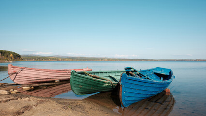 Obraz premium three colored old boats on the beach in the fall, pink, green, blue