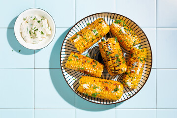Grilled corn cobs with butter, cheese and herbs,