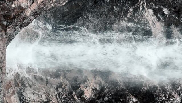 Waterfall of the Barskun gorge "Manas Bowl". A picturesque waterfall flows between dense spruce forests and rocks. Sun glare on the water. Splashes of water. Issyk-Kul region, Kyrgyzstan. 4K