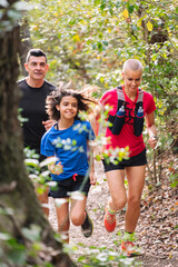 vertical photo of a family practicing trail running through the forest, concept of sport in nature...