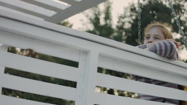 Little 8 yo girl having fun on a white swing in a quiet