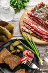 Tasty salt pork with rye bread, pickled cucumbers and dill on wo