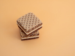 Delicious chocolate waffles with hazelnuts on an orange background. Wafers with chocolate and nuts.