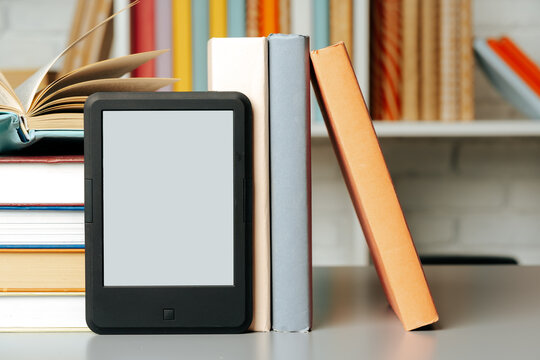 E-book reader on table against book shelves