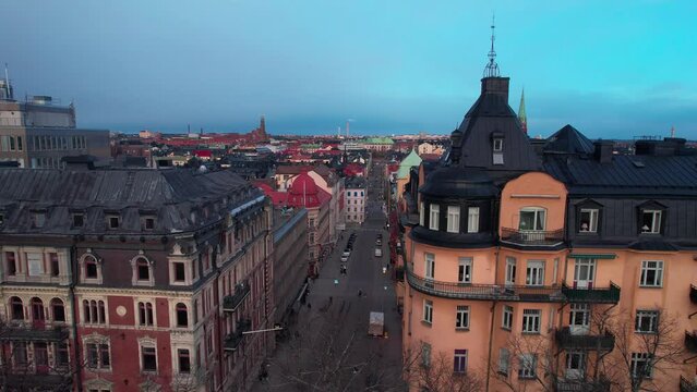 Drone shot revealing the cityscape of Stockholm old town, Colourful Swedish buildings architecture with busy streets, Cathedral in the evening