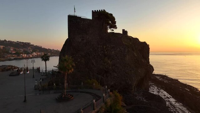Aci Castello e sullo sfondo le isole Ciclopi di Acitrezza. Sicilia, Italia, 
Vista aerea all'alba della costa vulcanica siciliana tra Aci Castello e Acitrezza.