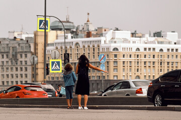 A woman with a boy hails taxi on a city street. Mom and son vote on the road.