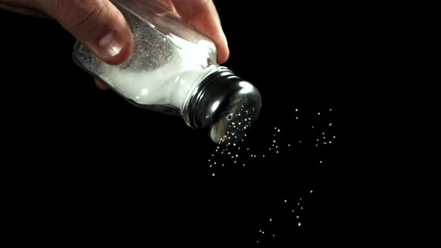 Salt falls from a salt shaker on a black background. Filmed on a high-speed camera at 1000 fps. High quality FullHD footage