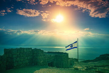 Beautiful sunrise over Masada fortress. Ruins of King Herod's palace in the Judaean Desert. The flag of Israel fluttering on Masada