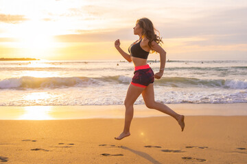 Sportive woman running along a sandy beach