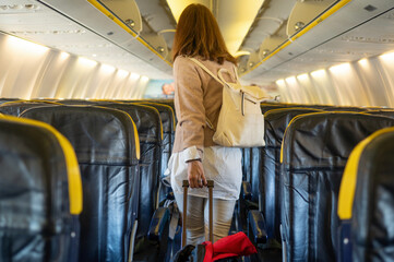 Unrecognizable female traveler with luggage entering airplane
