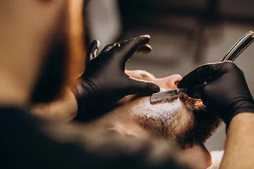 Foto op Canvas Handsome man cutting beard at a barber shop salon © Petro