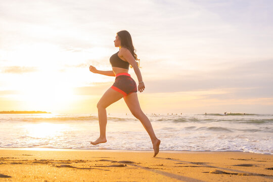 Young woman jogging along a beach during sunset