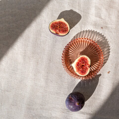 Minimal autumn background with fig fruits on linen tablecloth and harsh aesthetic sunlight shadows
