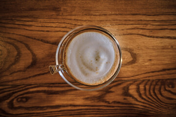 a cup of coffee with foam over wooden table, top view, selective focus.
