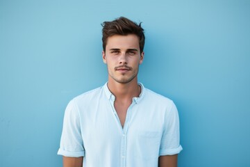 Fototapeta premium Attractive young man face on blue wall. Looking fashion person with big blue eyes. Generate Ai