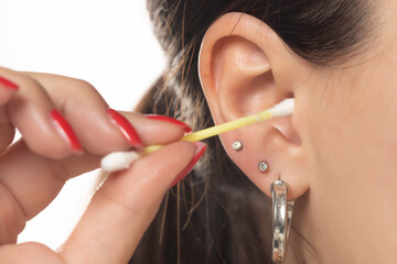 A woman cleaning her ear with cotton swab.
