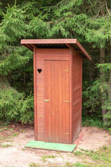 Forest hut or wooden toilet with a heart-shaped ornament in the middle of the forest