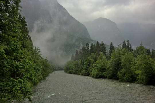 Traun river flowing through the mountains, Salzkammergut region in the Austrian Alps. Beautiful foggy and cloudy landscape with river and mountains in summer. Natural colorful background.