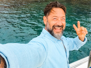One cheerful happy man with excited expression on face taking selfie picture standing inside a boat...