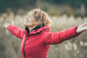One happy woman outstretching arms in outdoor leisure activity with nature field in background. Serene female people enjoying day and life. Healthy lifestyle wellbeing mindful concept person autumn - obrazy, fototapety, plakaty