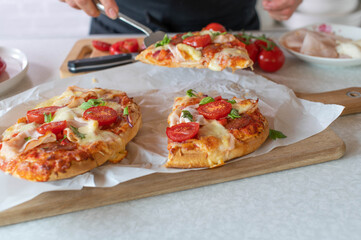 Woman serving a piece of pimped up pizza on a spatula in the kitchen 