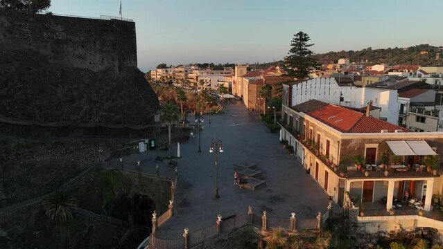 La piazza di Aci Castello, Sicilia, Italia.
Vista aerea all'alba del turistico paese marinaro sulla roccia vulcanica a picco sul mare.