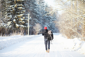 A man travels with a backpack. Winter hike in the forest. Tourist on a walk in the winter in the park.