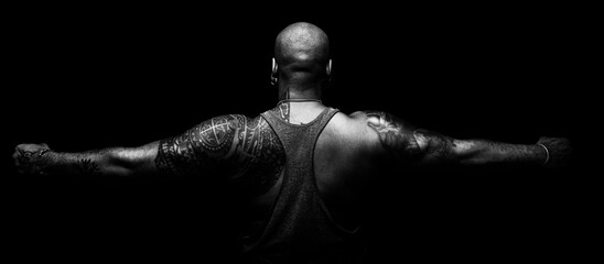 Back and arms of black man tattooed on black background in balnco and black - obrazy, fototapety, plakaty