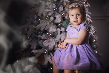 Fototapeta na wymiar Child in smart clothes in front of the Christmas tree. New Years Eve. Waiting for the new year.