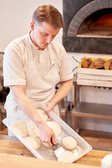 Dough for pizza, the chef rolls out the blanks. Closeup hand of chef baker in uniform white apron cook pizza at kitchen