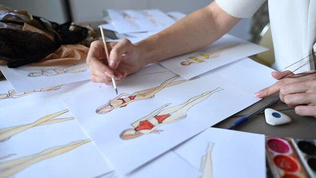 Faceless woman sketches swimwear and underwear. Close-up of fashion designer's hands.