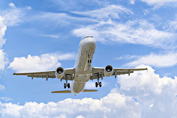 Airbus A321 passenger plane landing at the airport, under a blue sky with white clouds - obrazy, fototapety, plakaty