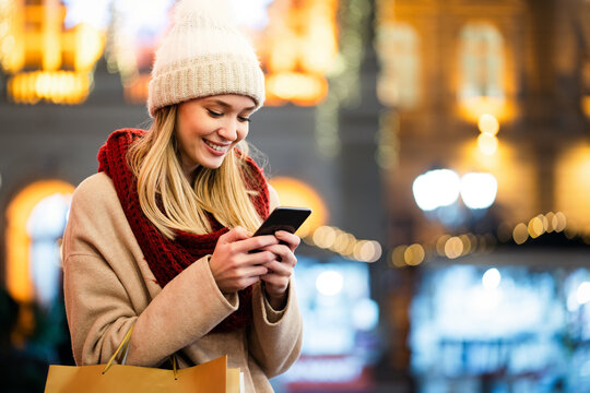 Portrait of smiling woman using mobile phone in the city at winter. People communication concept