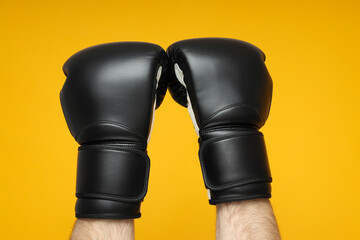 Black boxing gloves on a yellow background