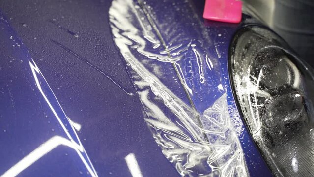 PPF Installation of a protective paint and varnish transparent film on the car. PPF polyurethane film to protect the car paint from stones and scratches. Car detailing. 