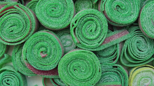 Colorful green fruit pastille  in a candy store. Zooming backdrop. Delicious and beautiful bright treats for children, extreme close up