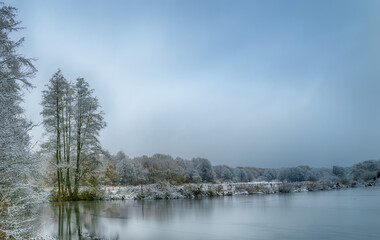 Fototapeta na wymiar Frozen lake in northern German countryside after snowfall in winter