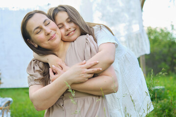 Amidst blooming flowers, a caring mother and her child enjoy relaxed conversations and heartfelt hugs in a backyard hammock.