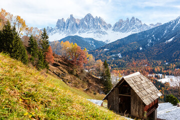 Fototapeta na wymiar Autumn rural mountain landscape with at аgricultural barn for hay in the foreground, Val di Funes, Dolomite Alps, South Tyrol, Italy.