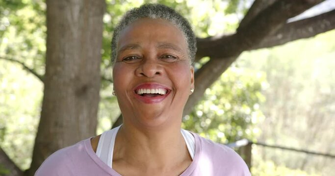 Portrait of happy senior african american woman smiling in sunny nature, slow motion