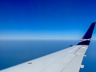 wing of an airplane in flight with blue sky on clear sky background. the horizon line seen from the plane.