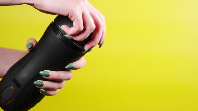 Sex toys for men. An artificial vagina for masturbation in the hands of a girl on a yellow background. Opens the lid with his hand. Male massager. Sex shop Adult store
