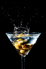 Olive splashing into a martini glass
